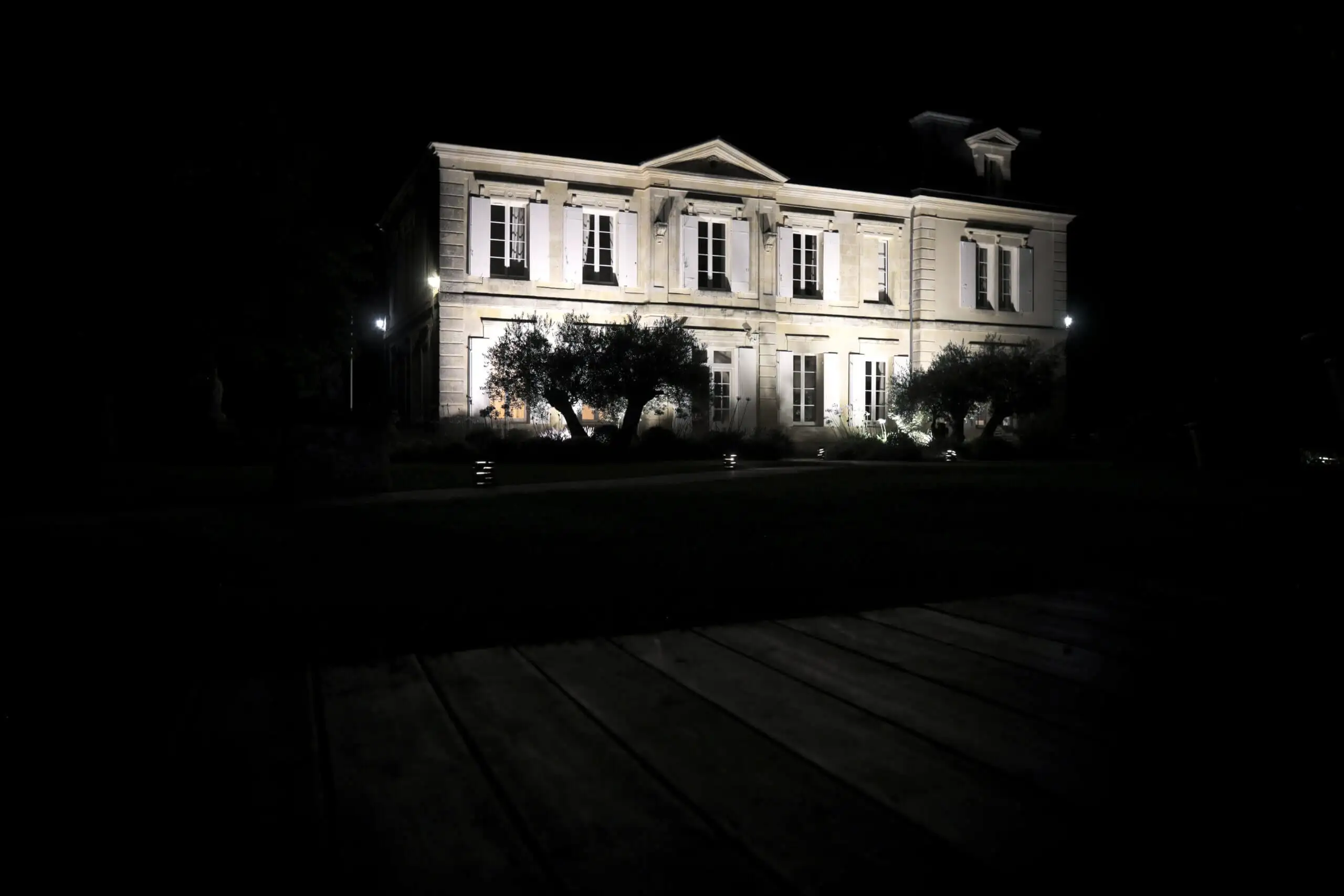 Château entièrement illuminé dans la nuit, vu depuis le parc