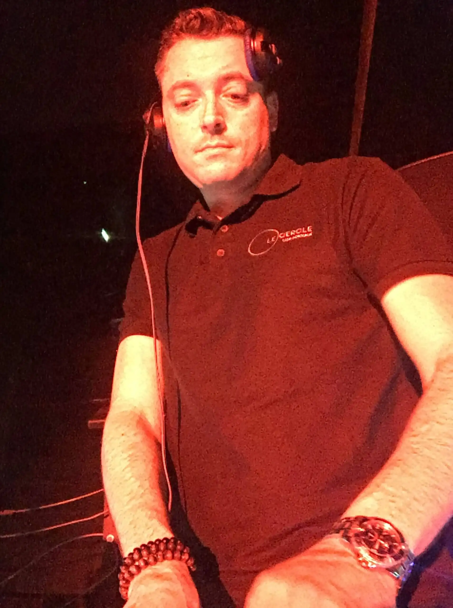 Tom Emersson aux platines dans une ambiance de club, lumière rouge