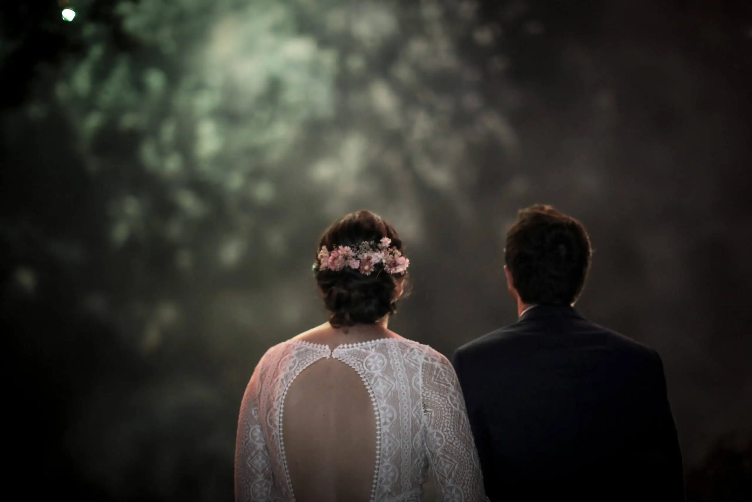 Les mariés de dos dans la nuit, silhouettes détourées par la fumée et les lumières
